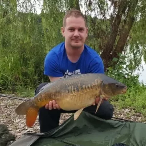 Shane Stanford holding a mirror carp on the bank